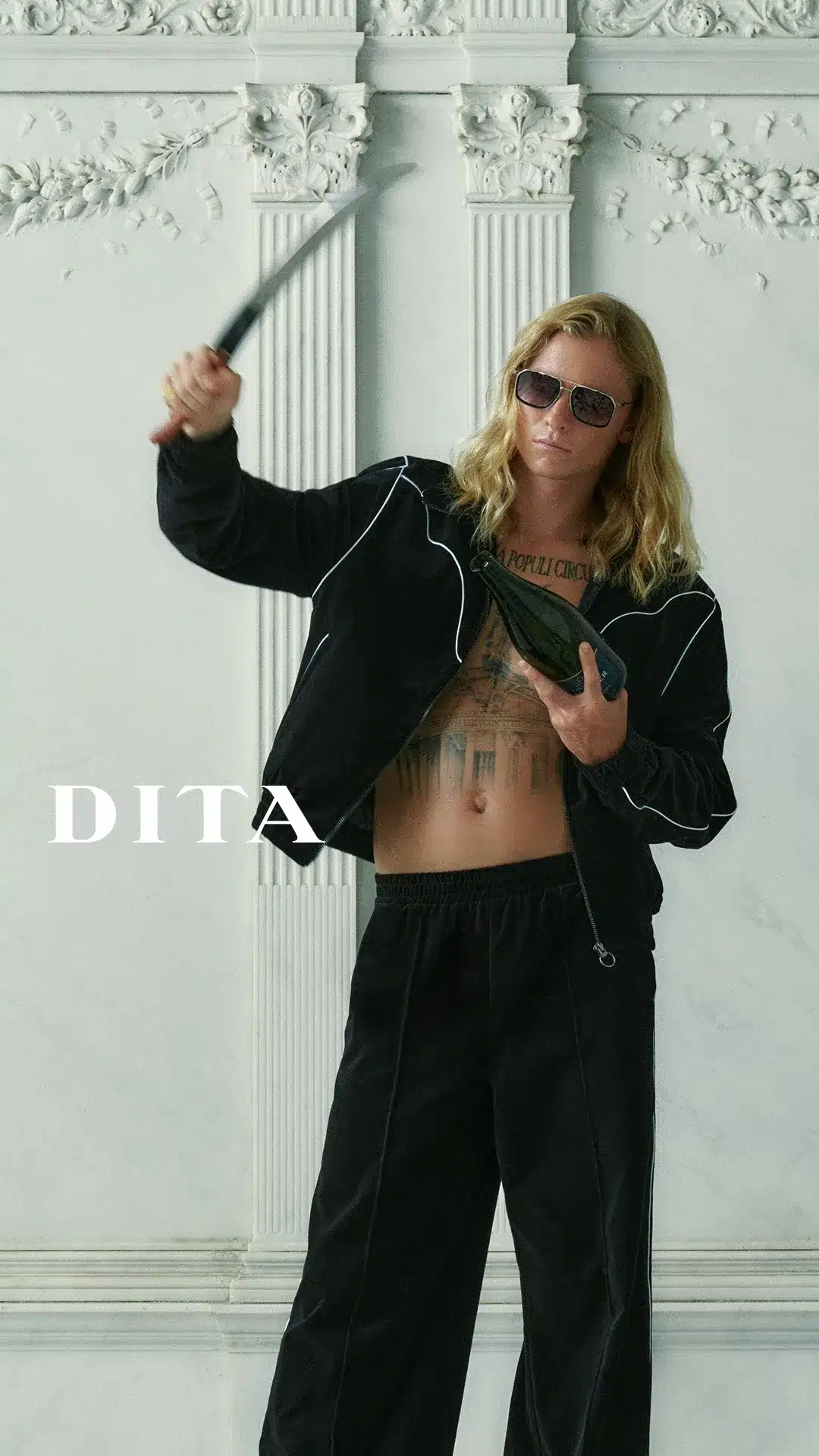 Model in DITA titanium aviator sunglasses holding a champagne bottle against a white marble wall