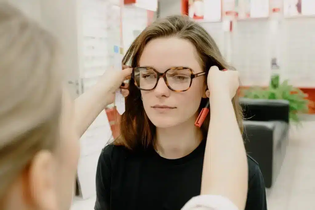 Woman wearing tortoiseshell-frame glasses while the frame is adjusted near her temples
